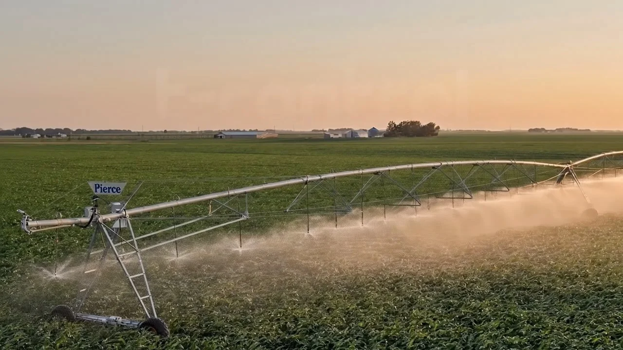 Pivote de riego en funcionamiento sobre un campo de cultivo al atardecer