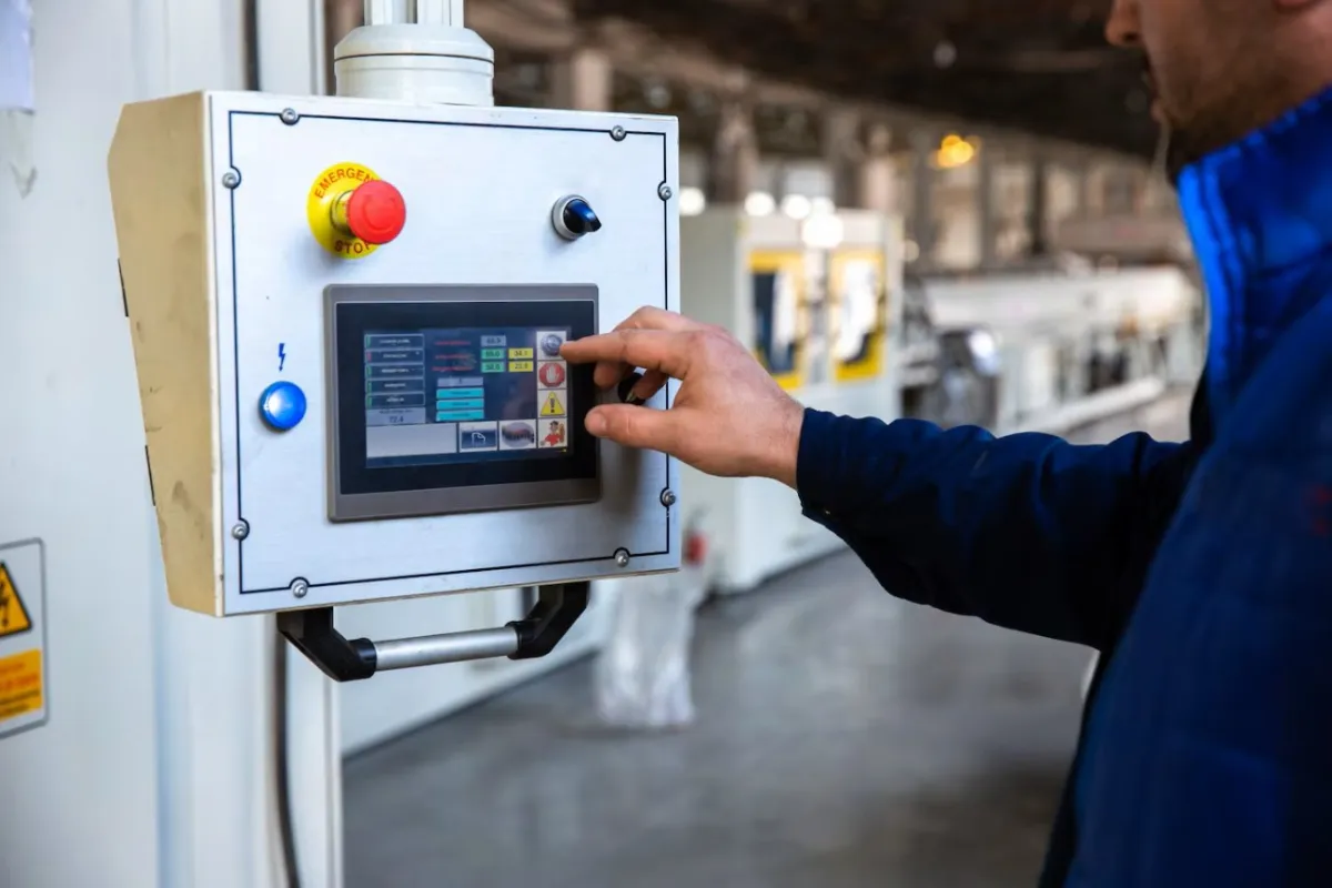 Operario usando el panel de control táctil de una máquina industrial