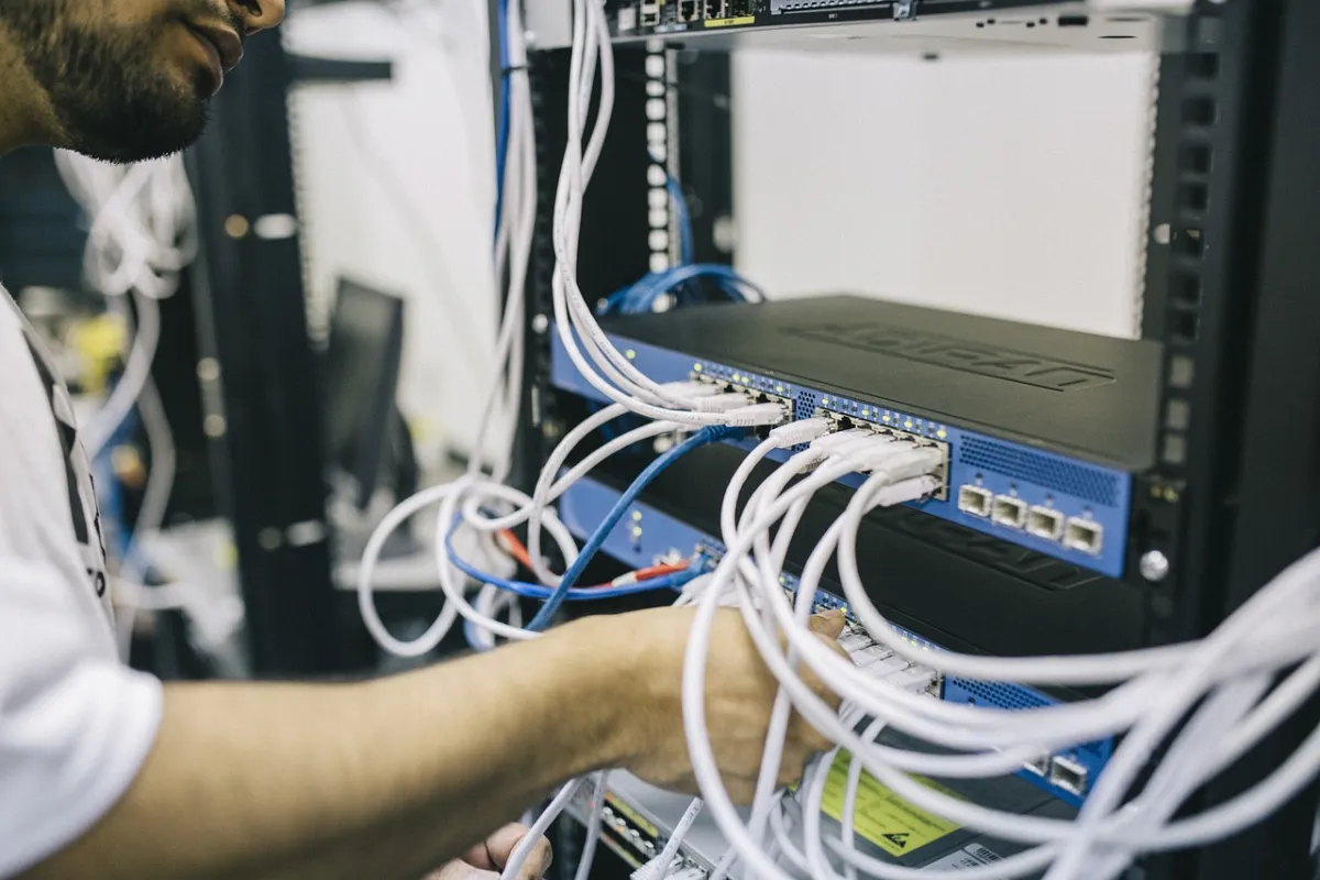 Técnico conectando cables de red en un rack de comunicaciones